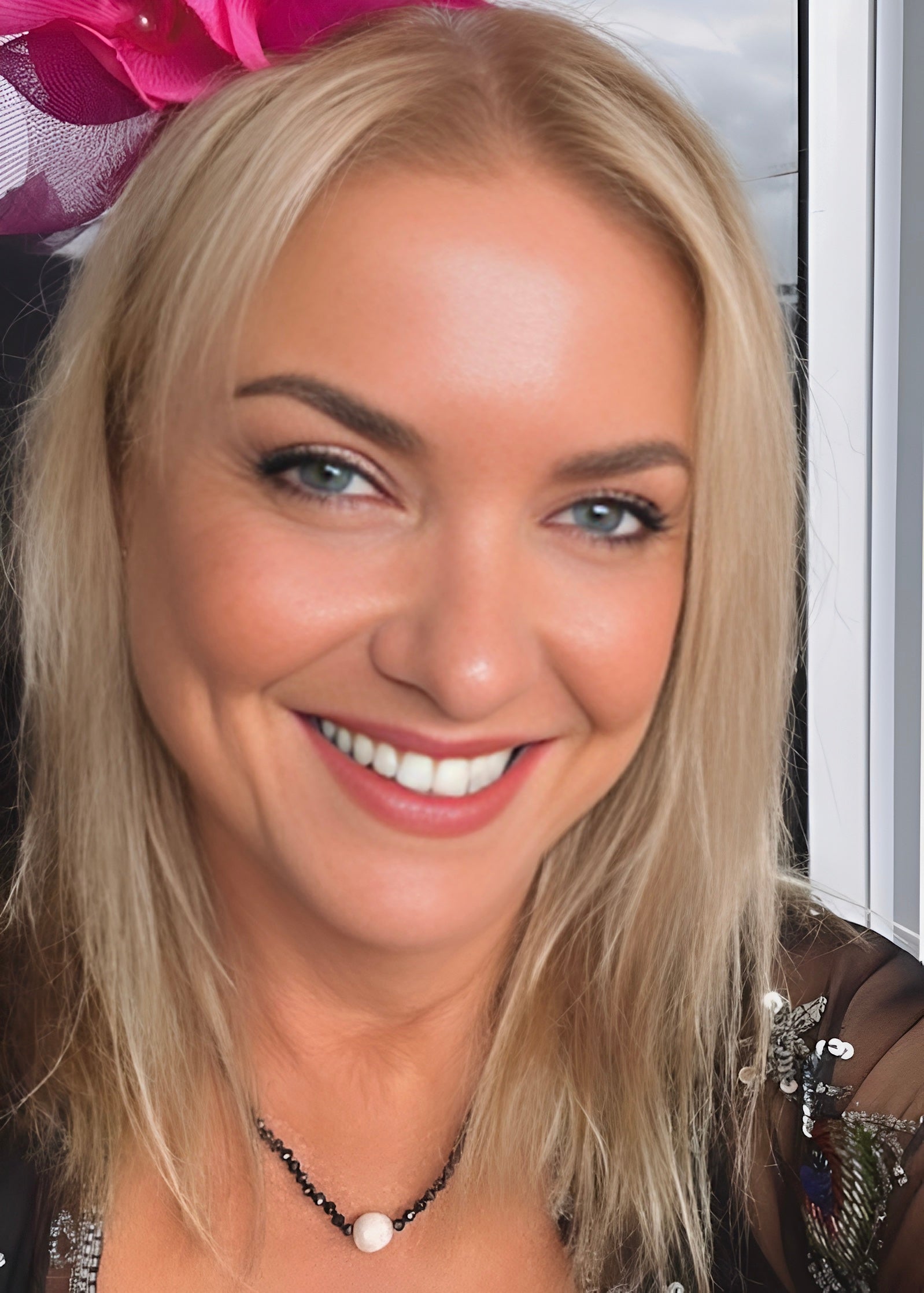Woman with blonde hair and a necklace, smiling.