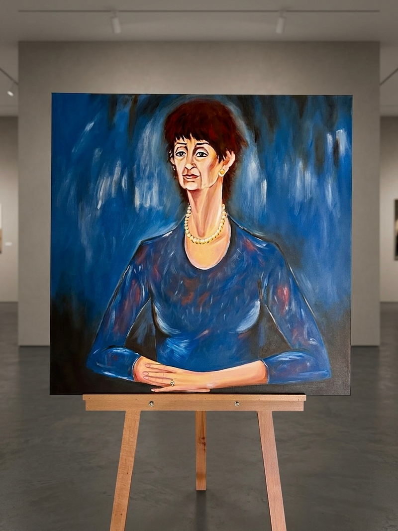 Painting of a woman in a blue dress on an easel in an art gallery.