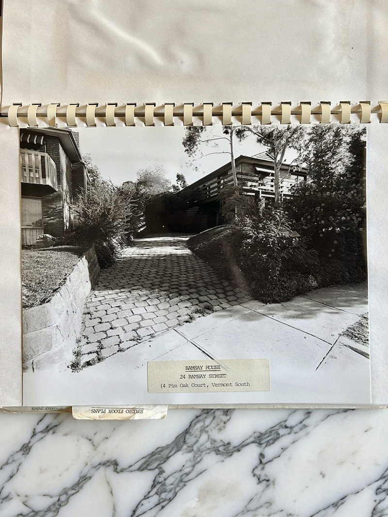 Vintage black and white photo of a house with a cobbled driveway, framed on a marble surface.