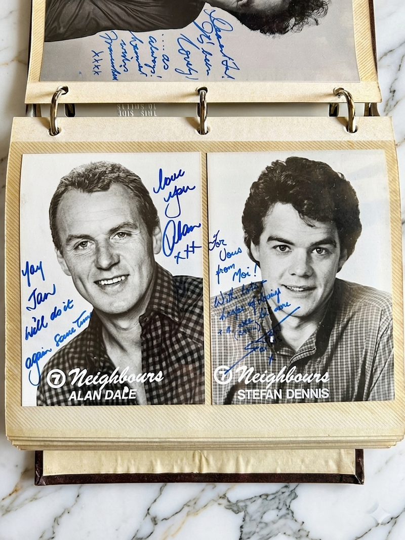 Autographed photos of two actors from 'Neighbours' on a display case with marble background