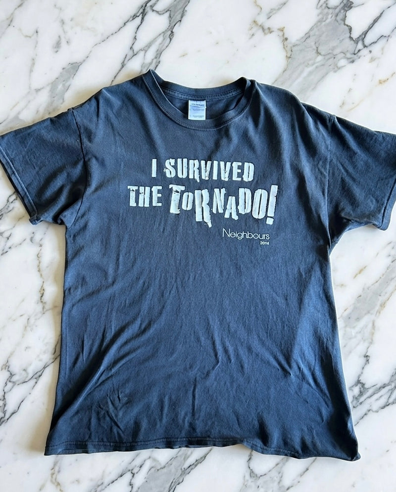 Blue t-shirt with 'I Survived the Tornado! Neighbours' text on a marble surface