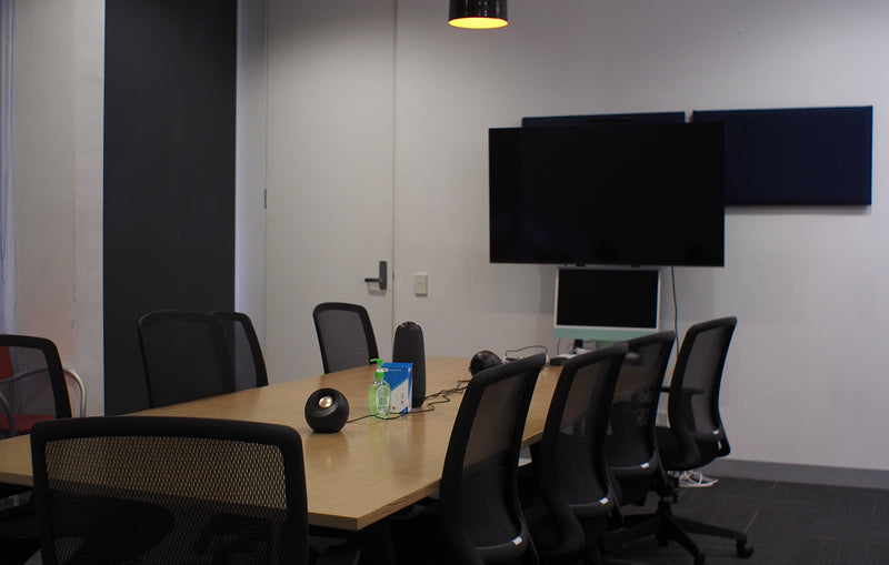 Modern conference room with a long table, chairs, and multiple monitors.