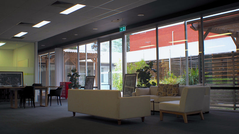 Modern office space with large windows, furniture, and outdoor view.