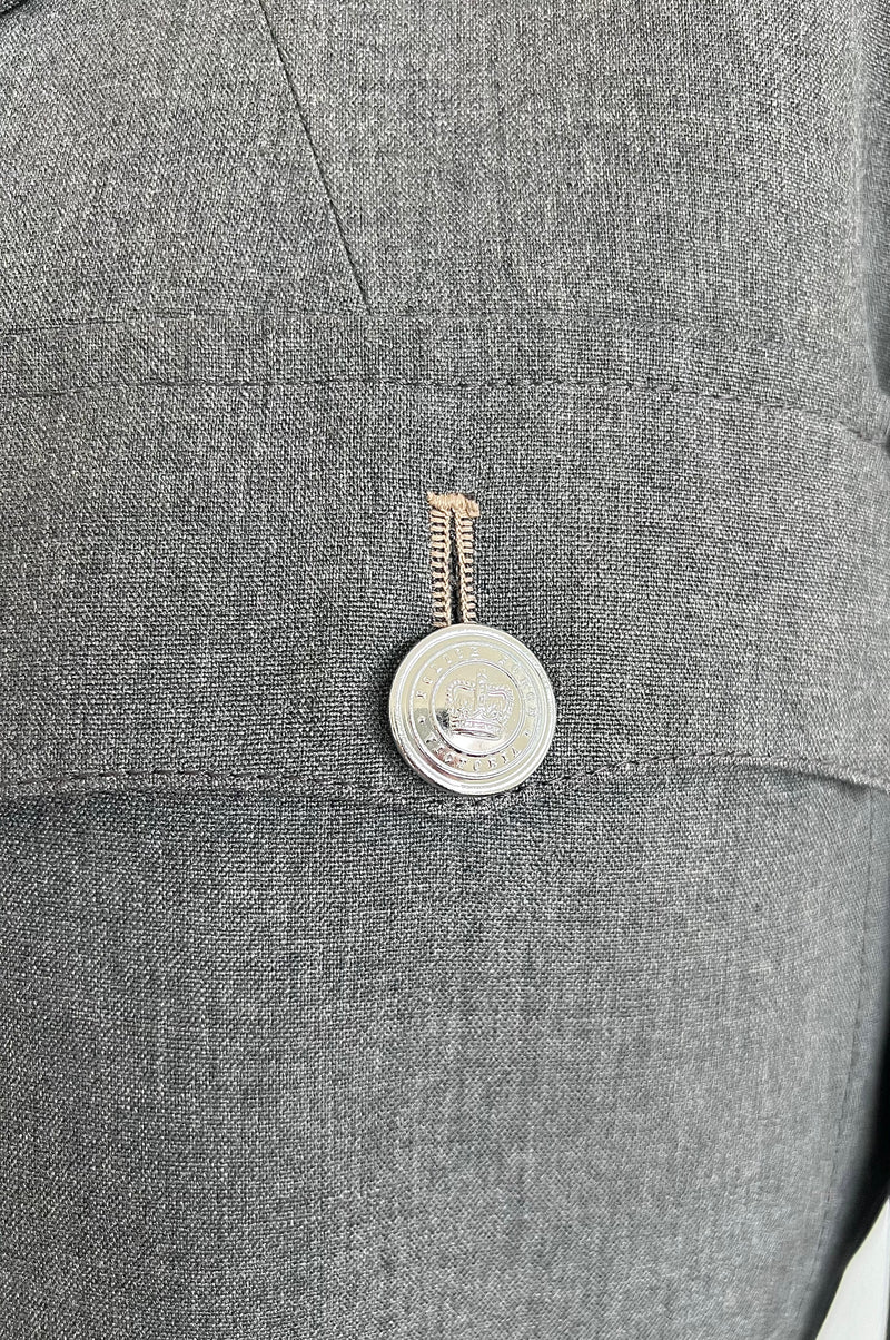Close-up of a button on a grey prison governor jacket with a coin design.