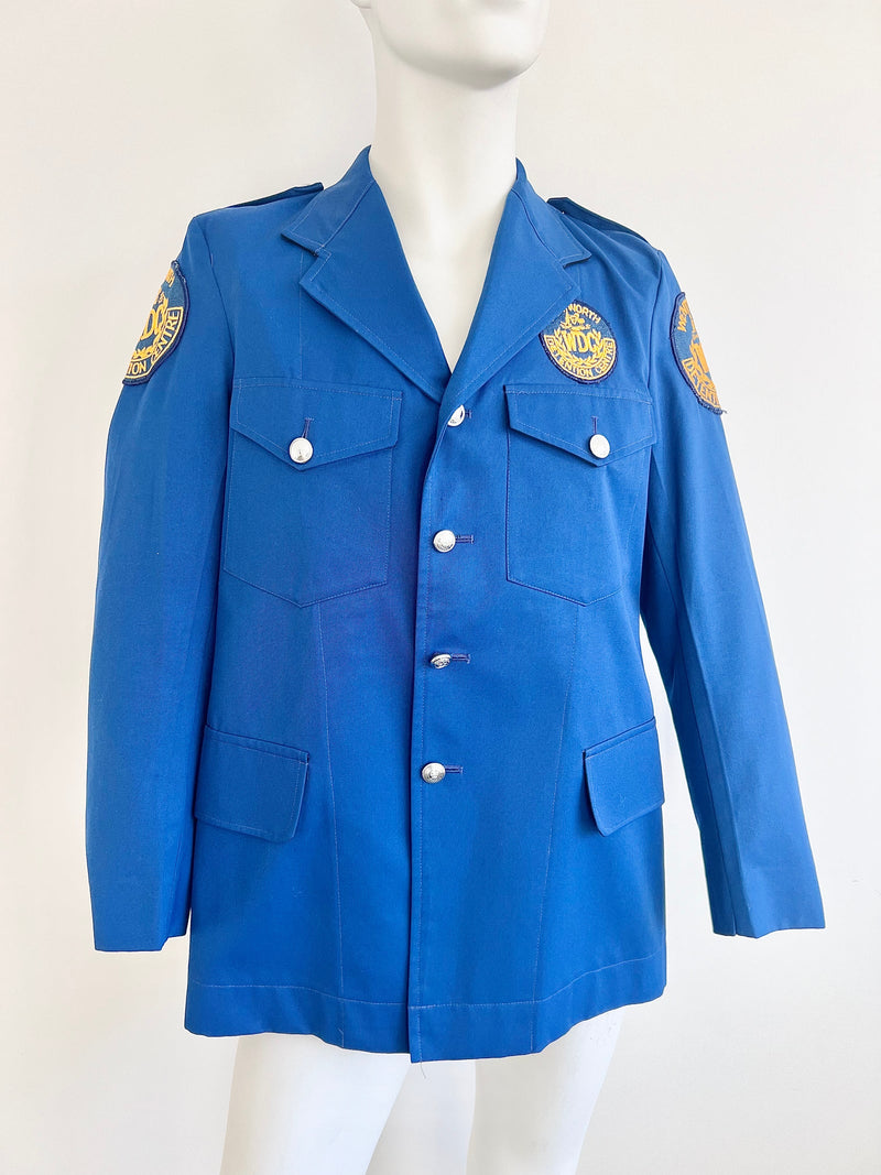 Blue guard jacket with gold patches on a mannequin against a white background