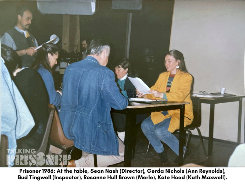 Group of people in a room with a table, one person signing a document.