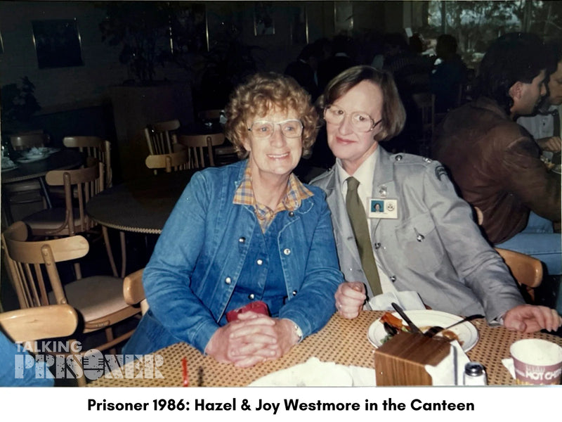 Two women sitting at a table in a canteen setting with text overlay about 'Prisoner 1986'.