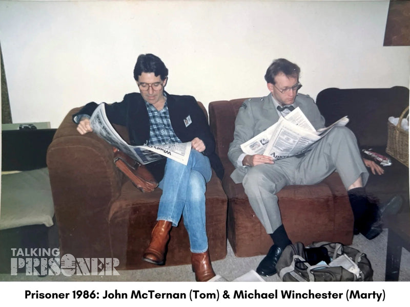 Two men sitting on a couch reading newspapers with text overlay indicating a TV show or movie reference.