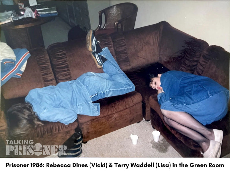 Two people in blue coverings sitting on a brown couch in a room labeled 'Green Room'.
