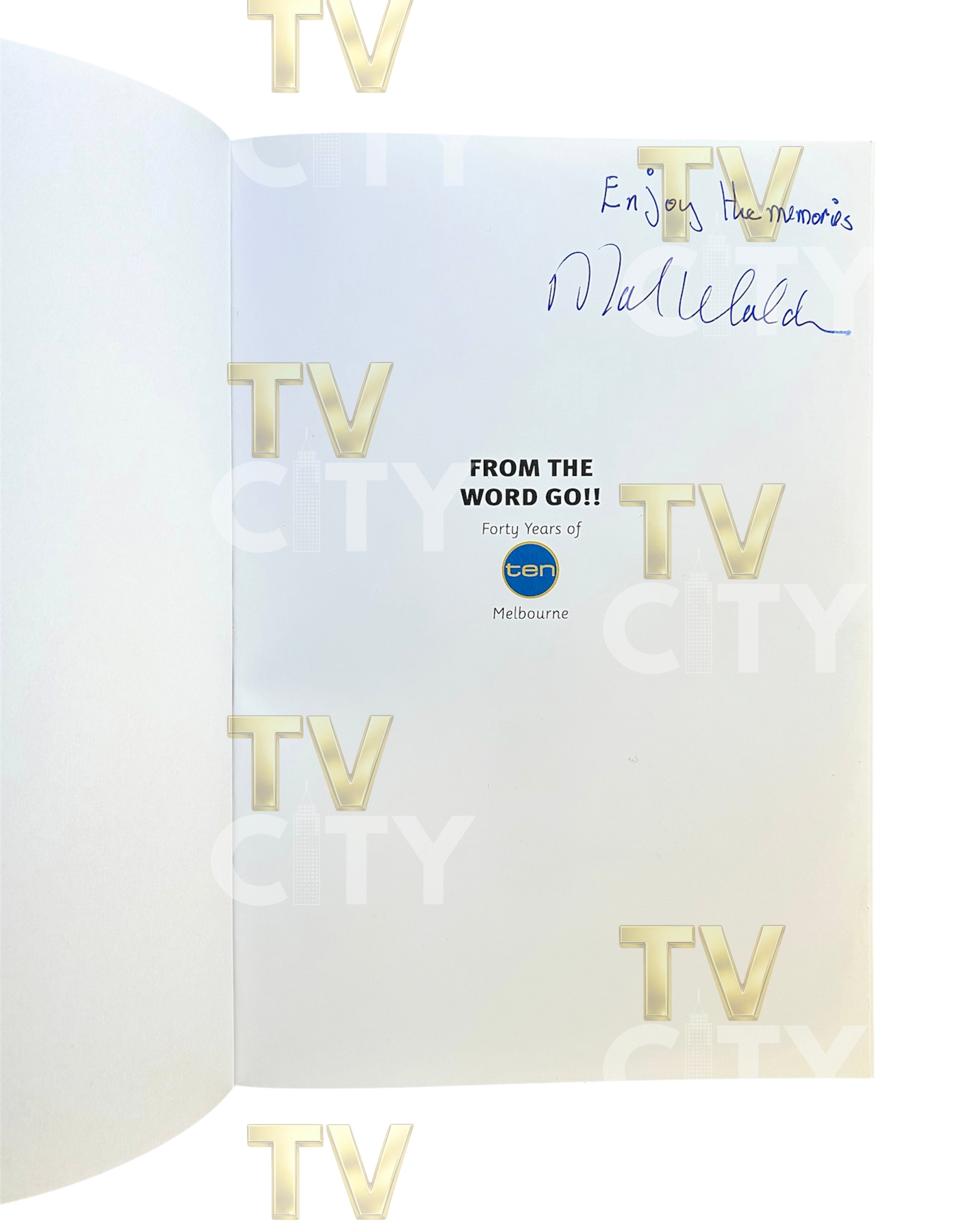 An open book or booklet showing an interior page with gold 'TV' logos repeated, a blue handwritten signature at the top right, and printed text reading 'FROM THE WORD GO!!' with a small blue circular logo in the center. The page is photographed against a white background.