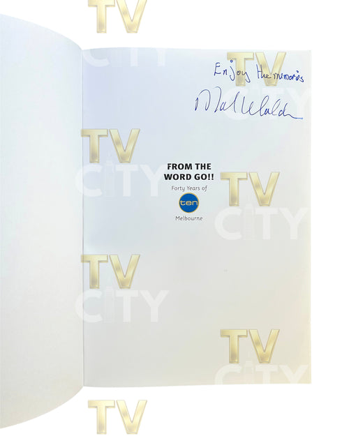 An open book or booklet showing an interior page with gold 'TV' logos repeated, a blue handwritten signature at the top right, and printed text reading 'FROM THE WORD GO!!' with a small blue circular logo in the center. The page is photographed against a white background.