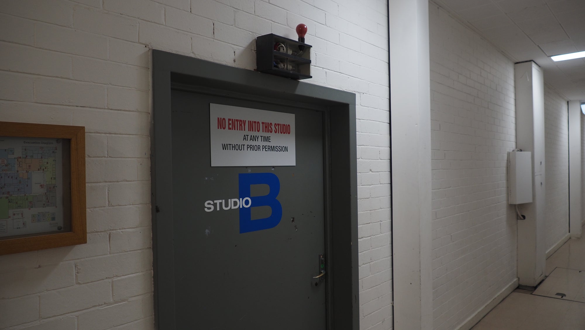 Door with 'Studio B' logo in a hallway with white walls and a framed picture.