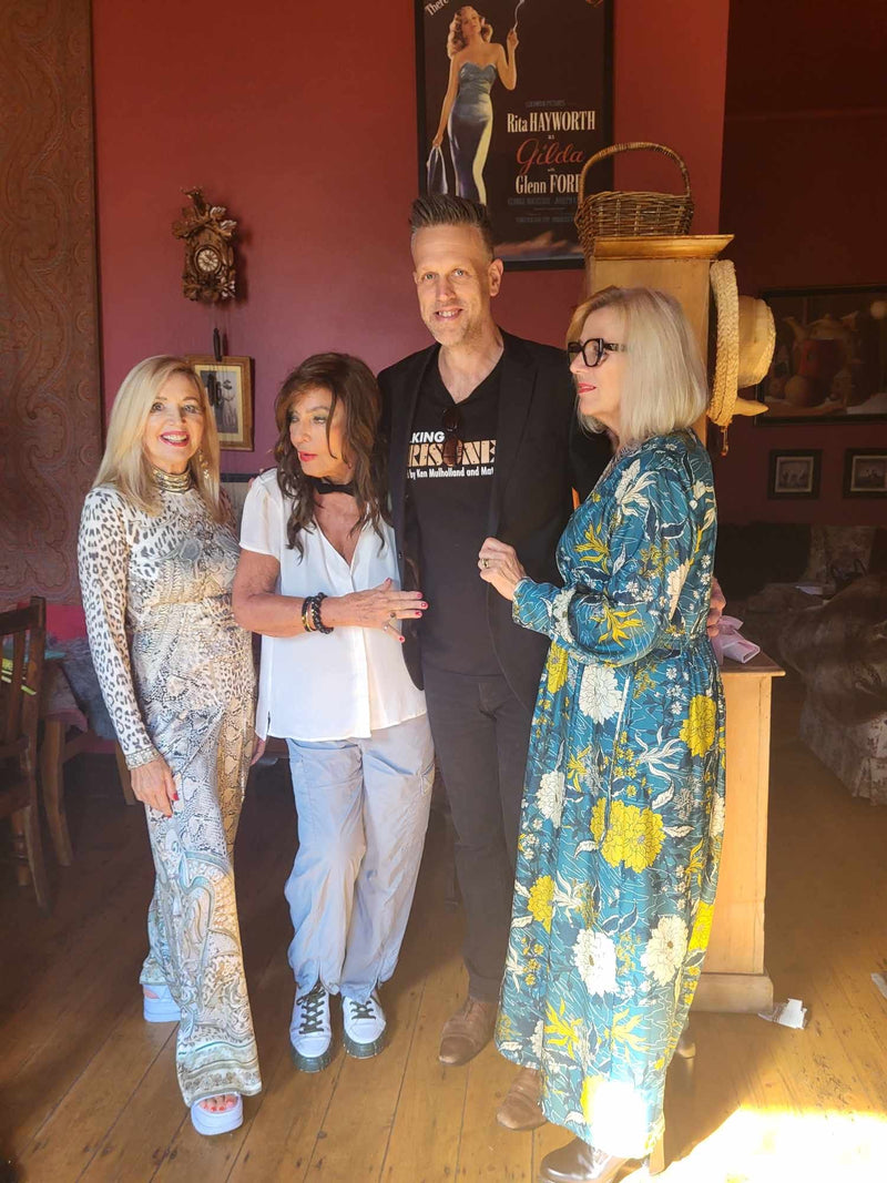 Four people posing together in a room with decor and furniture.