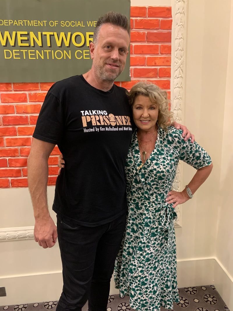 Two people standing in front of a brick wall with 'Wentworth Detention Centre' text.
