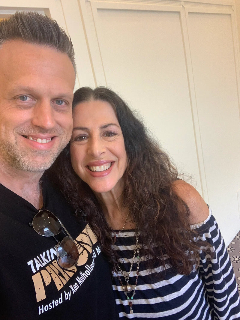Two people posing for a selfie indoors with a neutral background