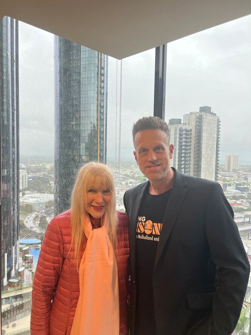Two people standing in front of a large window with cityscape view