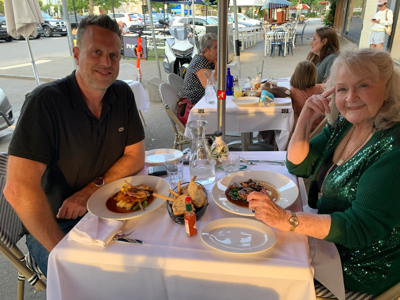 Two people sitting at a table outdoors with plates of food
